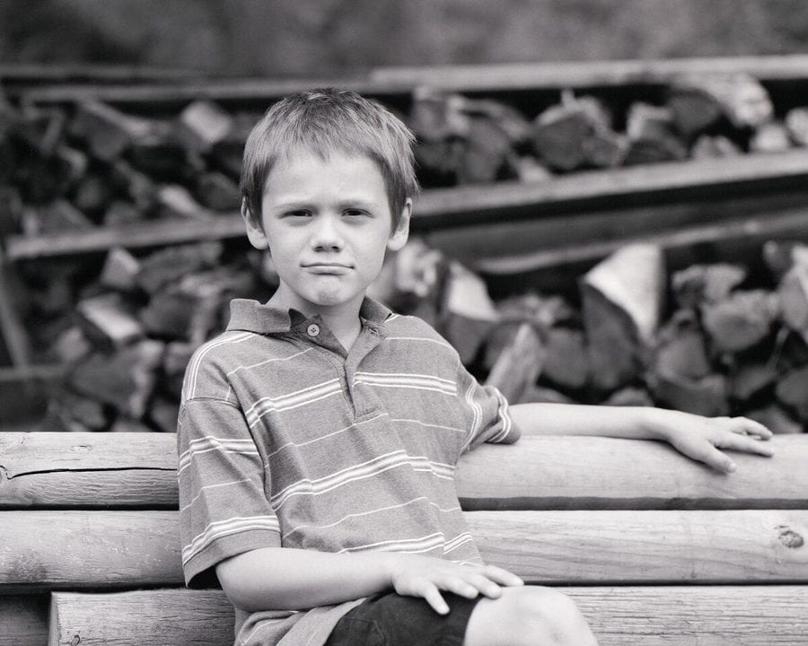 Boy seated by the tracks in black and white